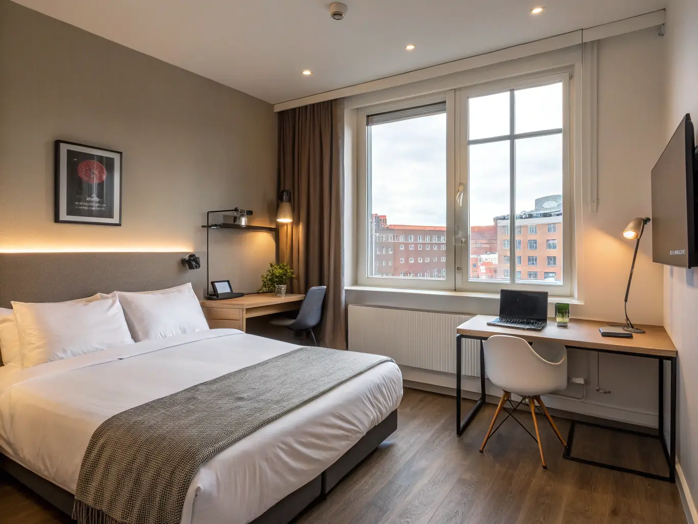 A modern and stylish private room at Aalborg Hostel, featuring a comfortable double bed, a work desk, and a large window offering natural light, creating a relaxing and private space for couples or solo travelers.