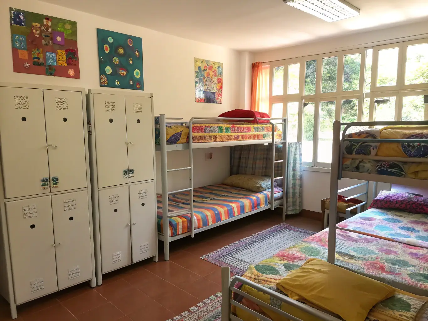 A brightly lit and welcoming dormitory room at Aalborg Hostel, featuring comfortable bunk beds, individual reading lights, and secure personal lockers, creating a social and safe environment for budget travelers.